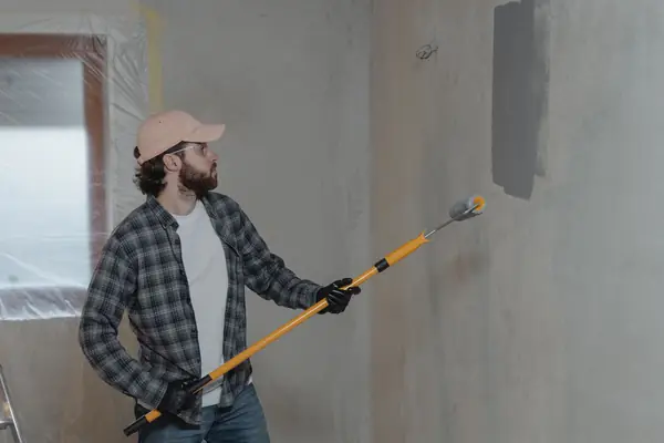 Painter rolling grey paint onto an interior wall in Reno